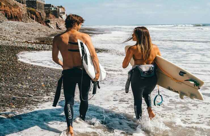 ragazzo e ragazza con tavola da surf sulla spiaggia